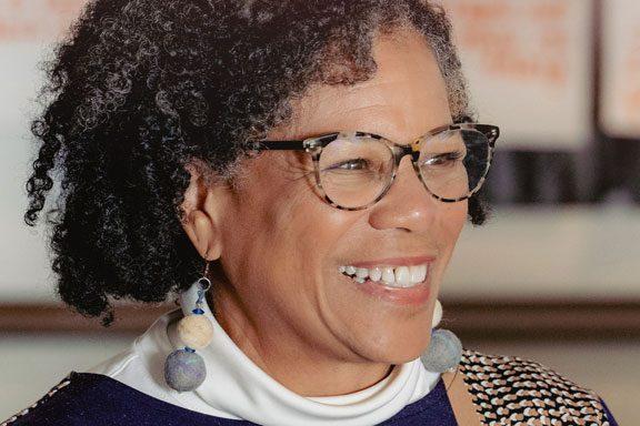 A woman smiles looking across the room.